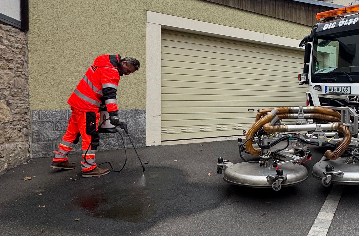 Mann reinigt eine Straße mit einer Flüssigkeit